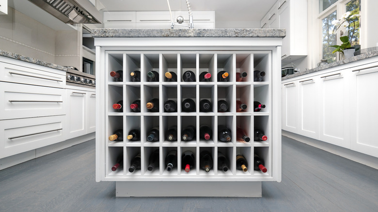 Adanın içine yerleştirilmiş şarap şişesi deposuna sahip modern mutfak