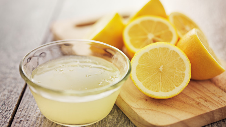 kesilmiş limonların yanında bir kapta limon suyu