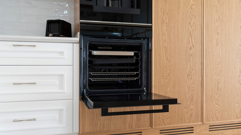 Ahşap dolaplı mutfakta açık kapılı ankastre fırın