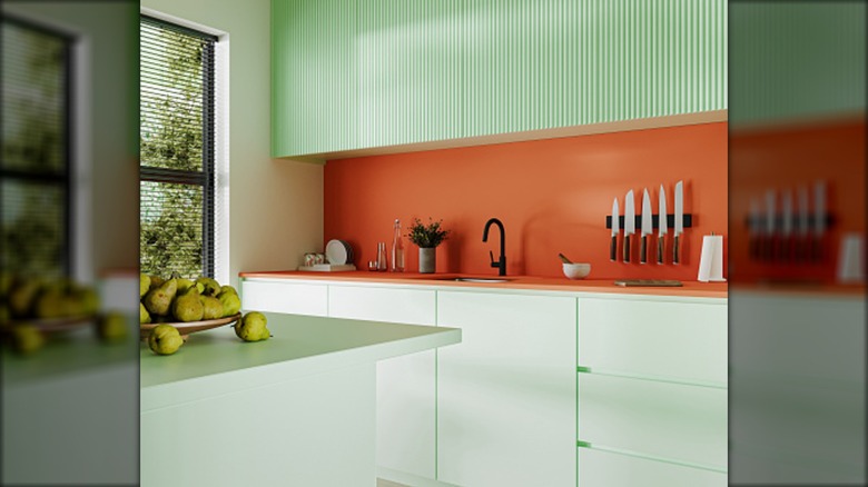 Kil renginde backsplash ve nane yeşili, yivli dolaplara sahip bir mutfak.