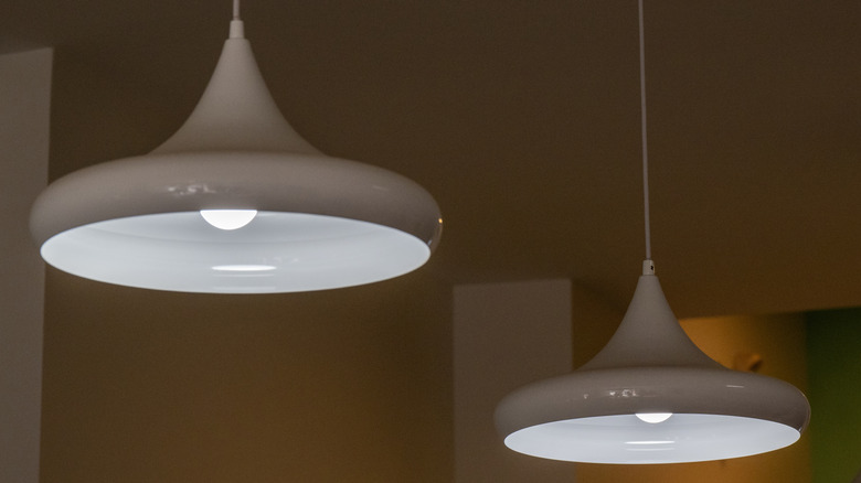 Tavanda bir çift beyaz, koni şeklinde damla kolye.