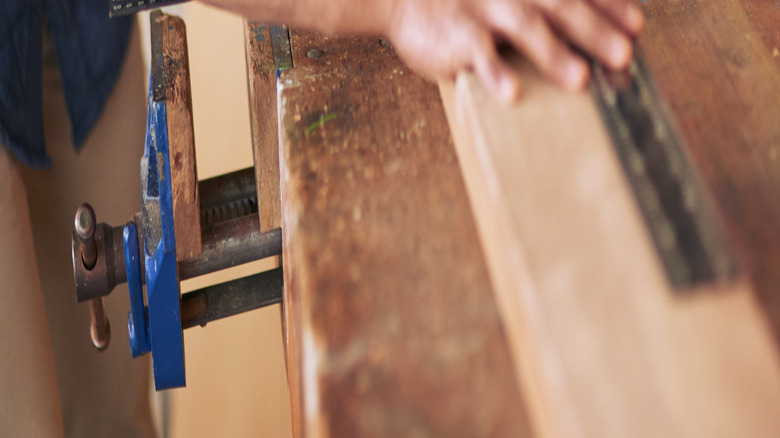 Bir kişi ahşap bir tahtayı ölçer