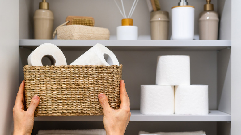 Banyo dolabının içinden sepeti çıkaran kişi