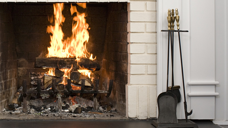 Alevli bir ateşin yanında pirinç kulplu şömine aletleri seti