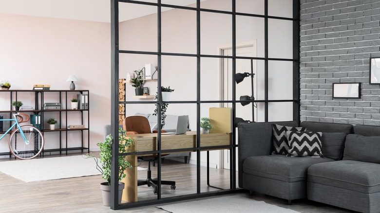 Ev ofisi ile oturma odası arasında oda bölücü olarak koyu renkli, metal açık pencere çerçevesine sahip şık, modern ev