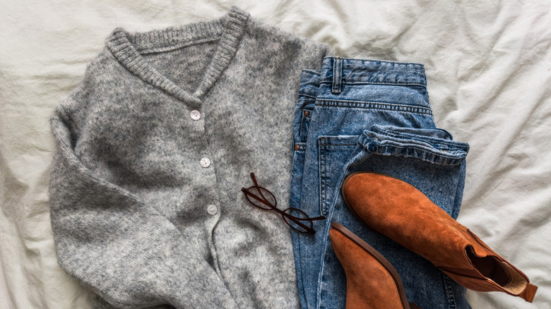 kaşmir kazak, kot pantolon, botlar ve yatakta uzanan gözlük