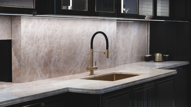 Bej granit tezgahlı ve siyah dolaplı mutfak lavabosu