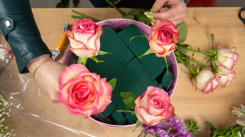 İçinde sahte çiçekler bulunan bir masanın üzerinde duran çiçek köpüğü.