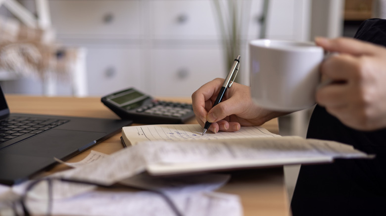 Bütçe üzerinde çalışan ve masada oturup kahve içen kadın