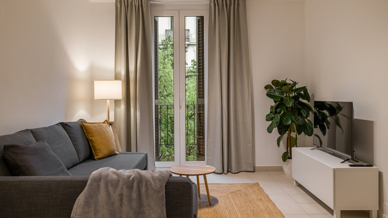 küçük oturma odasında balkon penceresinin önünde uzun perdeler