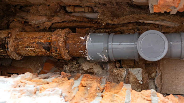 Eski dökme demir kanalizasyon hattının bir kısmını değiştiren PVC boru