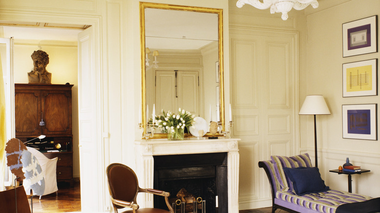 Siyah beyaz şöminenin üzerinde asılı büyük yaldızlı bir aynanın bulunduğu zarif bir iç mekan.