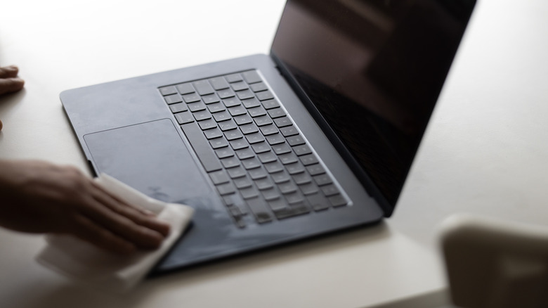 Dizüstü bilgisayarın klavyesini silen kişi