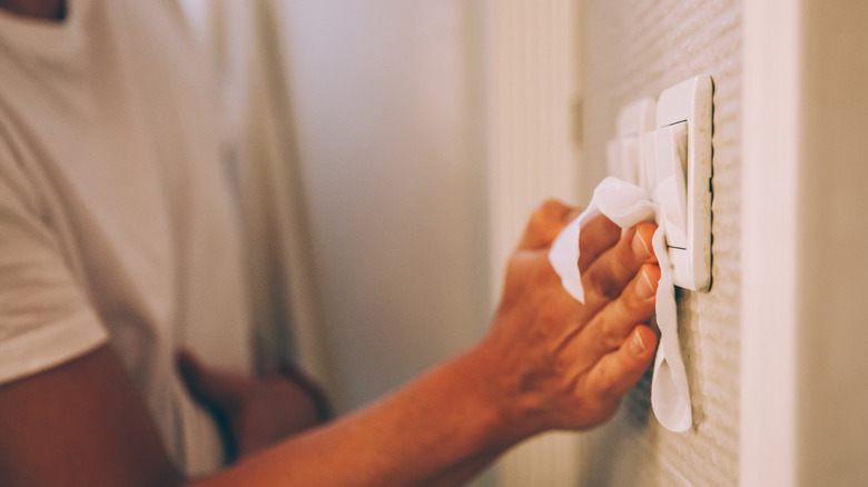 ışık anahtarını mendille temizleyen kişi