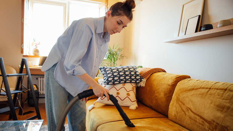 bir kadın kanepesini süpürüyor