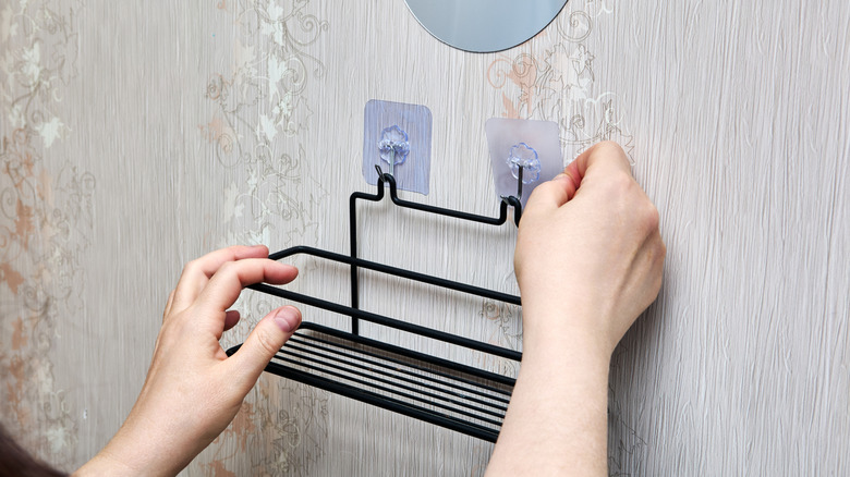 Metal sepeti duvara asan kişinin yakın çekimi