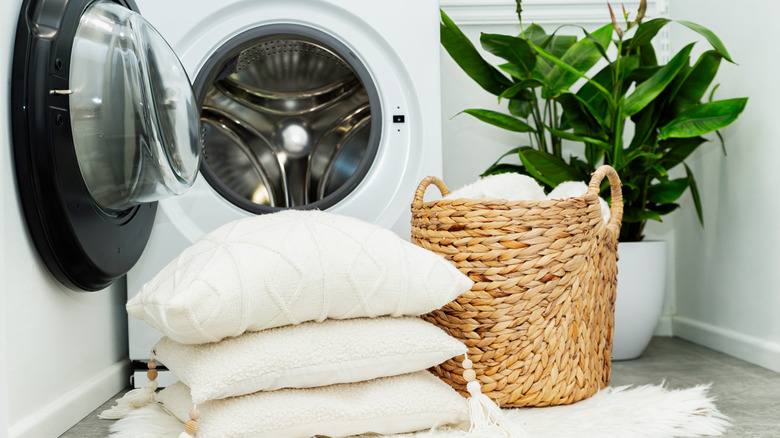 çamaşır sepetinde yatak takımı ve çamaşır makinesinin dışında yastıklar