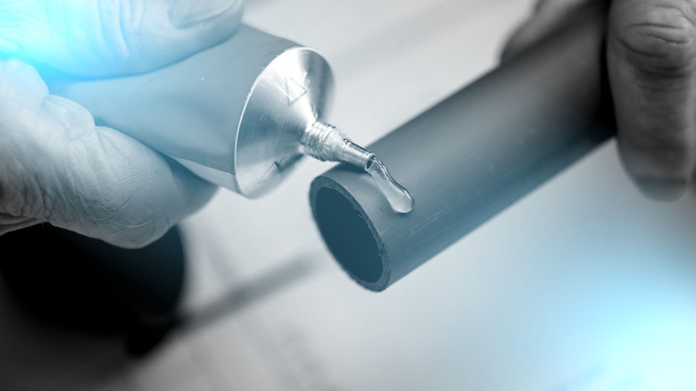 Borunun ucuna tesisatçı tutkalı süren bir kişi