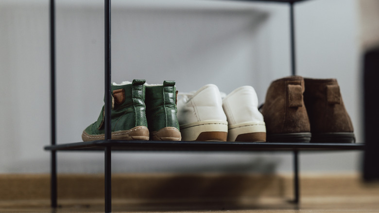 Üç çift ayakkabıyla dolu metal ayakkabı rafı.