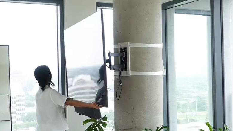 Sütunlara monte edilmiş büyük ekran TV'yi tam hareketli montaj düzeneğine çeviren kadın