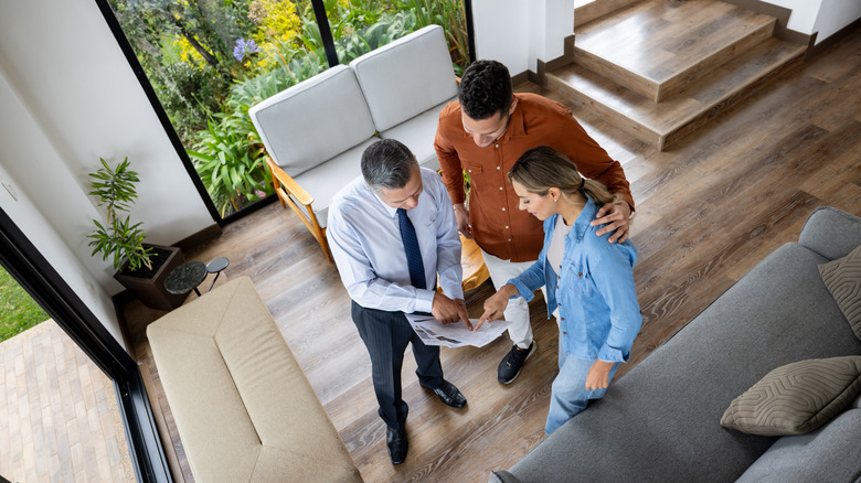 Müşterilere ev planını gösteren bir emlakçının üst görünümü