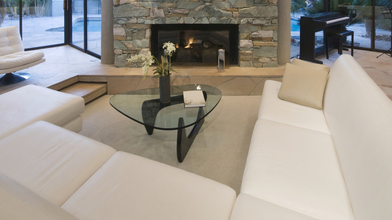 1970'ler tarzı, merdivenli, minimalist mobilyalı ve şömineli gömme oturma odası.