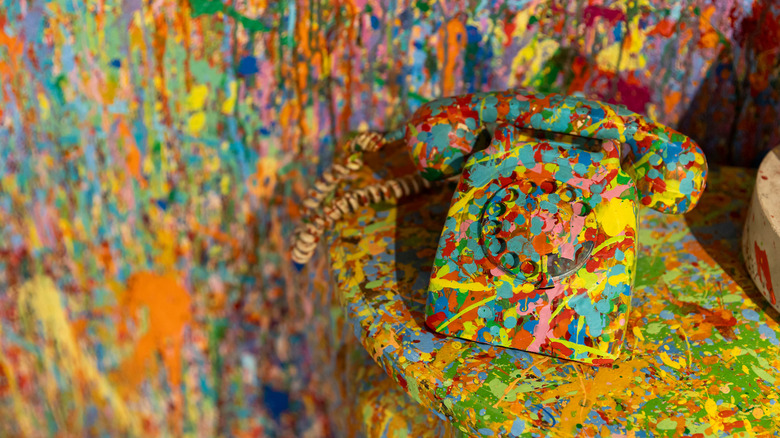 Duvarlarda ve masada sıçrayan boya bulunan bir masanın üzerinde sıçrayan boyalı döner telefon