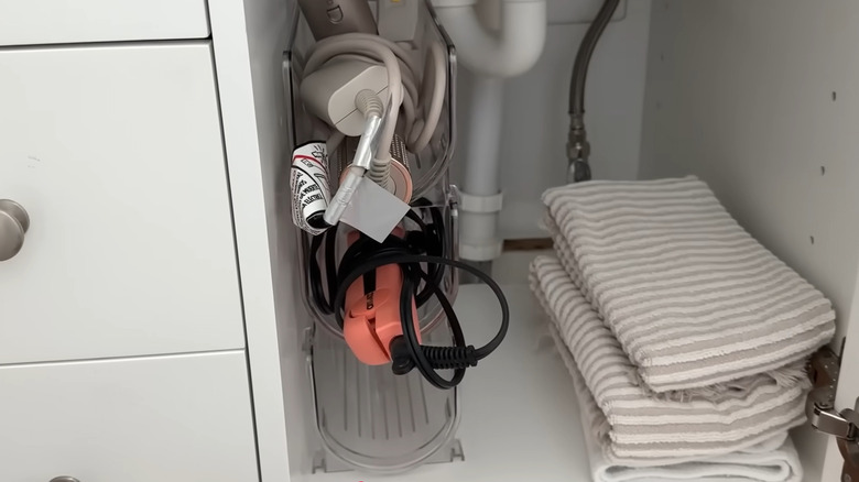 Saç şekillendirme aletleriyle birlikte banyo lavabosunun altına yığılmış şarap şişesi tutucuları