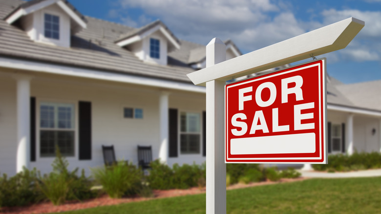 siyah panjurlu ve satılık tabelalı beyaz ev