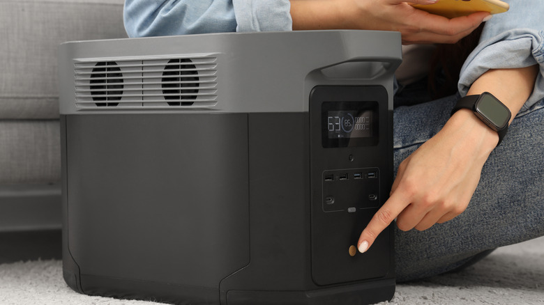 Evde taşınabilir bir elektrik santralini açan bir kişi