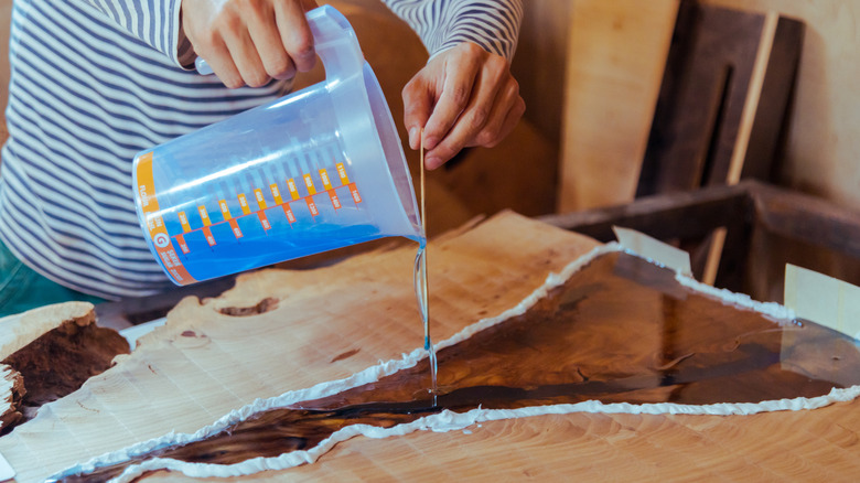 Ahşap boşluklarını epoksi reçineyle dolduran bir kişi.