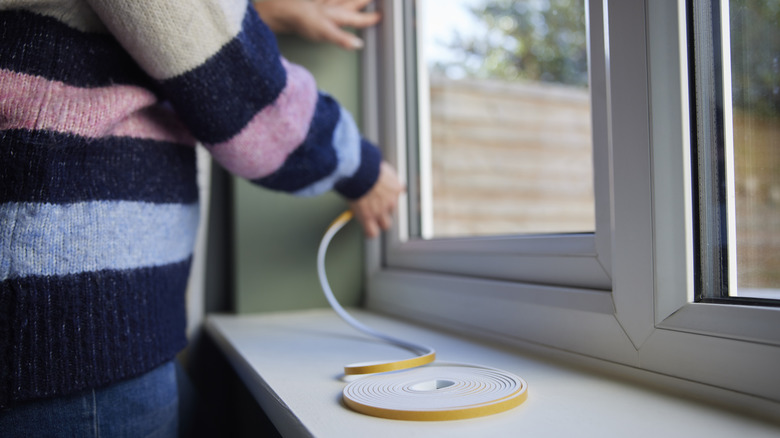 Ev sahibi pencere yalıtım kitini takıyor.