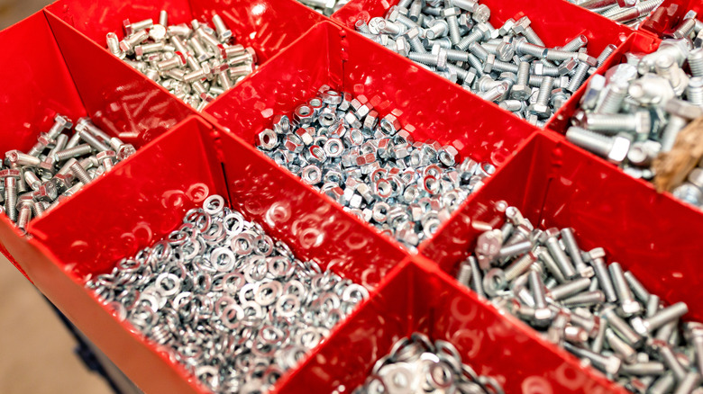 Somunlar, cıvatalar ve pullarla dolu kırmızı metal düzenleyici