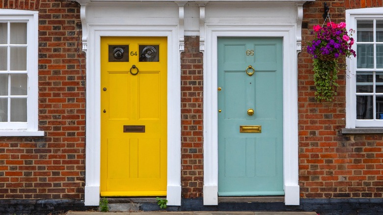 Biri sarı, diğeri mavi-yeşil olmak üzere iki apartman kapısı olan kırmızı tuğlalı bir ev
