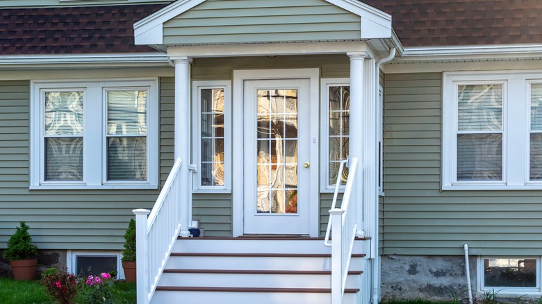 Bir evde bir dizi merdivenin önünde beyaz ahşap ve cam bir ön kapı