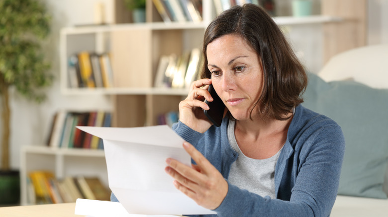 Kağıt parçası tutarken telefonda konuşan kadın