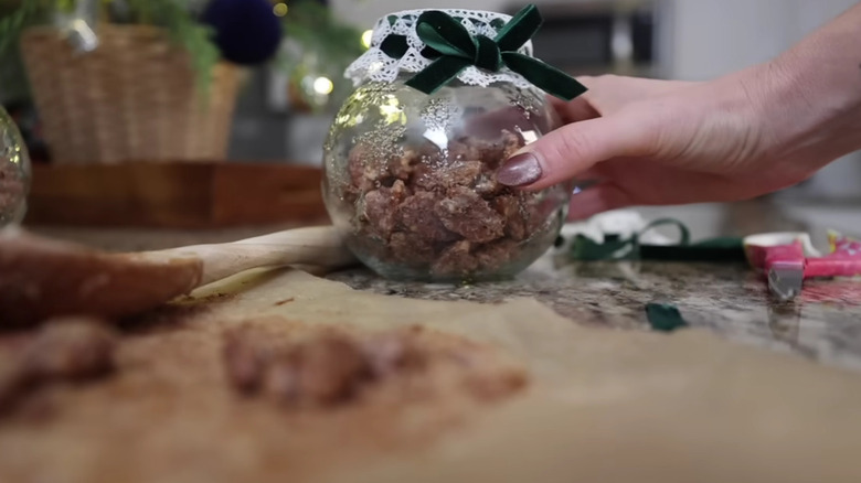 Fındık şekeriyle dolu bir cam kavanozu tutan bir el.