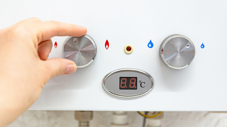 Su ısıtıcısında sıcaklığı ayarlayan kişi