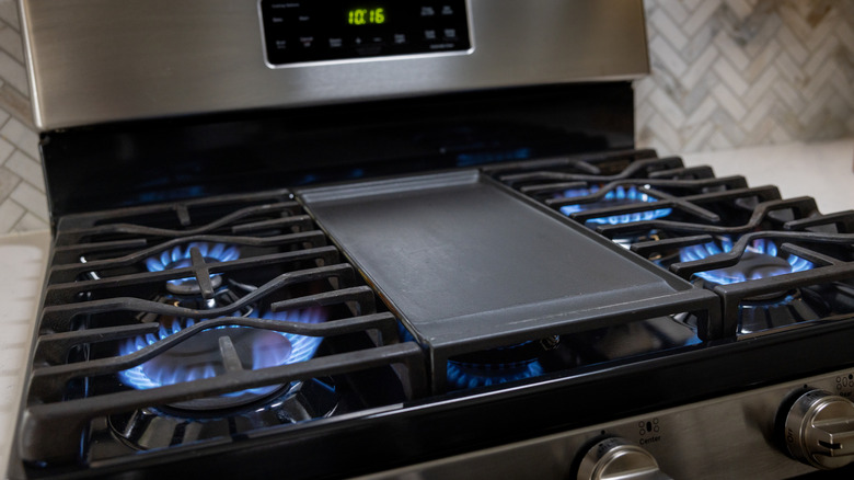 Beş ocağın hepsinin açık olduğu ve mavi alevlerin olduğu bir gazlı ocak.