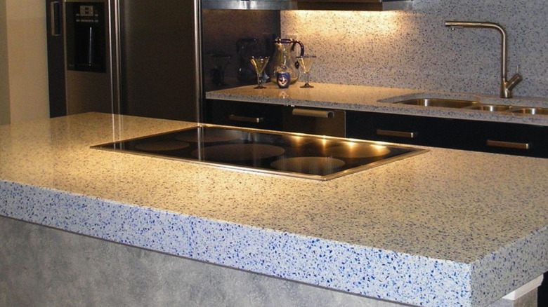 Tezgah aralığı ve paslanmaz çelik aletlerin bulunduğu modern bir mutfakta mavi ve beyaz geri dönüştürülmüş cam tezgah.