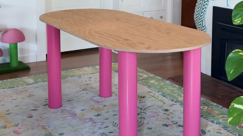Meşe kontrplaktan ve sprey boyayla pembeye boyanmış PVC borudan yapılmış büyük bir masa.