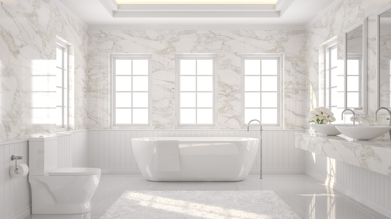 Zemin kaplaması ve çiçeklerle donatılmış tuvalet, küvet ve lavabo içeren modern banyo