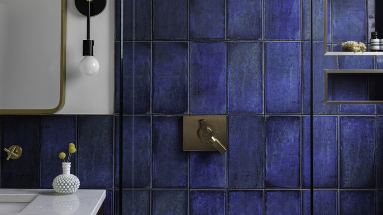 Gümüş, altın ve siyahı aynı duvarda koyu mavi çini ile birleştiren banyo metal özelliklerinin yakından görünümü