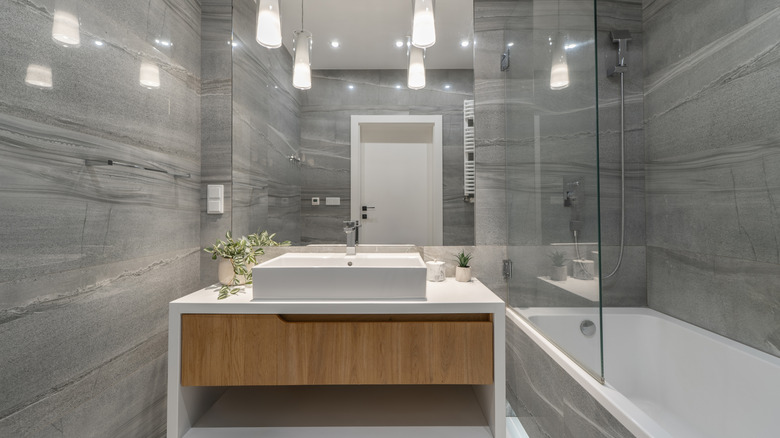 Sert tavan ışıklarına sahip gri banyo tasarımı