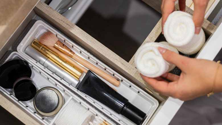 Makyaj fırçalarıyla çekmece düzenleyicisine pamuk mermileri yerleştiren el