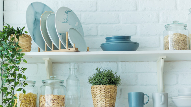 Bir tuğla duvara karşı açık raflarda duran mavi tabaklar