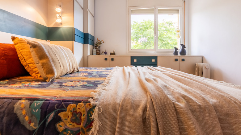 Rengarenk desenlerden oluşan desenli bir yorgan ve üstüne ince bir battaniyenin yerleştirildiği bir yatak