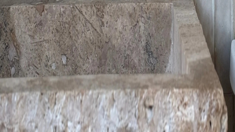 Beyaz zellige fayanslı backsplash ve yumuşak altın musluklu kireçtaşı lavabo.