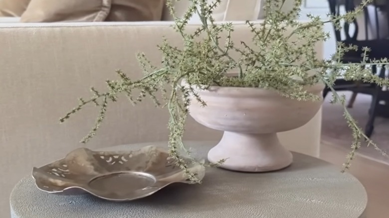 Dalgalı kenarlı krom tepsi, yan sehpayı süslüyor.