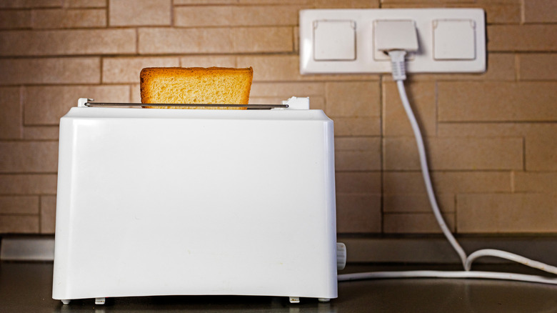 Beyaz bir ekmek kızartma makinesi prize takılı
